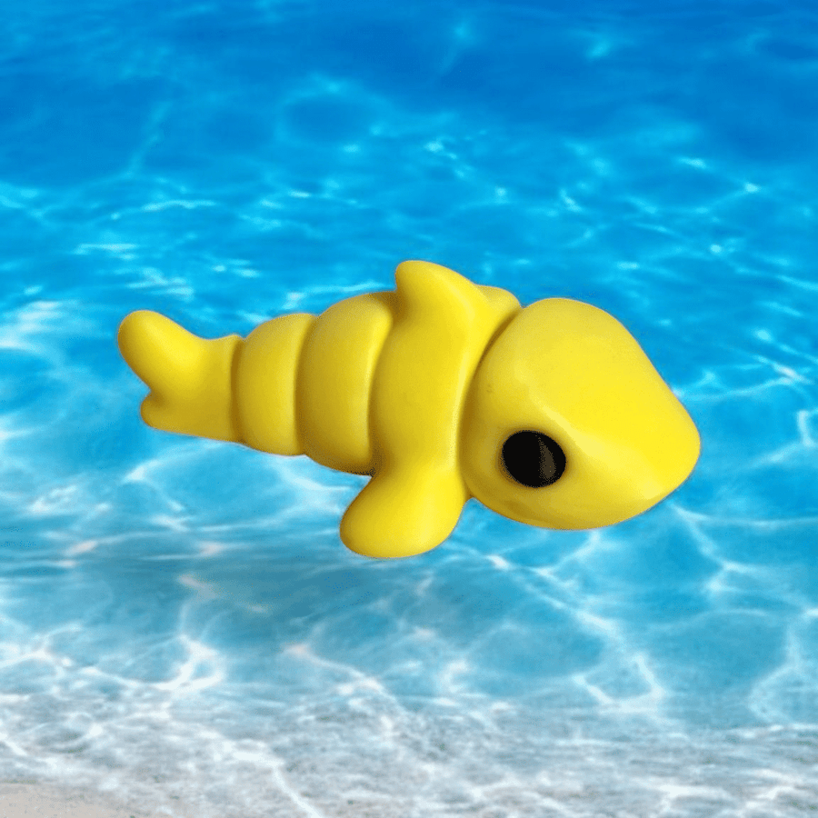 A toy yellow shark floating in the ocean near the edge of the beach.